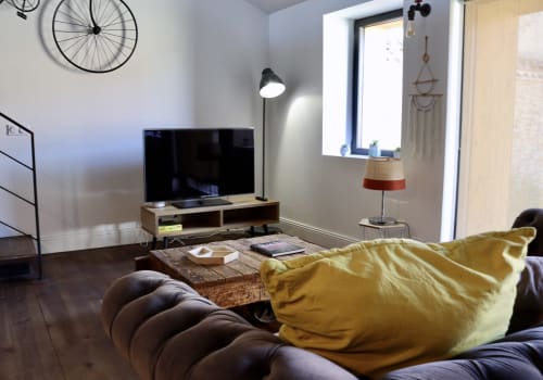 Modern loft living room at La Maison d'Augustin with sofa, TV, garden views, and contemporary furnishings