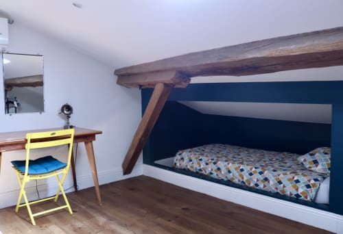 Loft bedroom at La Maison d'Augustin with built-in bed, wooden beams, yellow chair, and desk in Mont-de-Marsan