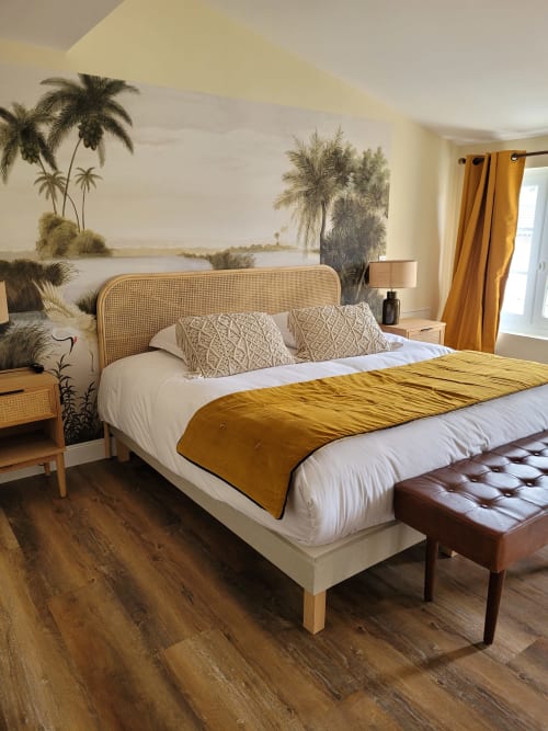 Luxurious bedroom at Pavillon Des Millesimes with rattan headboard, golden accents, tropical mural, and city view in Lussac