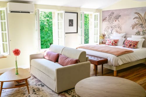 Studio luxueux au Pavillon Des Millesimes à Lussac avec canapé crème, lit king, papier peint botanique et vue sur le jardin