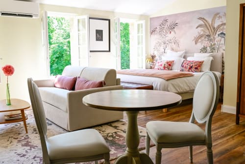 Luxurious studio deluxe bedroom at Pavillon Des Millésimes with seating area, botanical wallpaper, and garden views