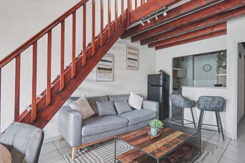 Modern loft apartment at Emmlea with gray sofa, wooden staircase, kitchen, and bar seating in Tresserve