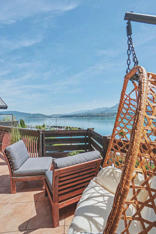 Suspended balcony at Emmlea overlooking Lake Bourget with wooden swing, lounge chair, and sailboats