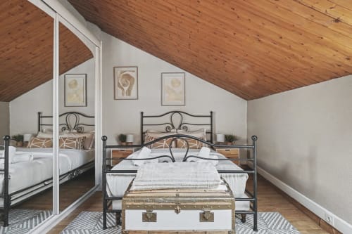 Modern bedroom with metal bed frame, wooden ceiling, mirror, and lake views at Emmlea hotel in Tresserve