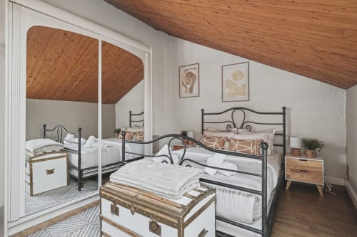 Cozy bedroom at Emmlea in Tresserve with twin metal beds, wooden ceiling, and mirrored closet