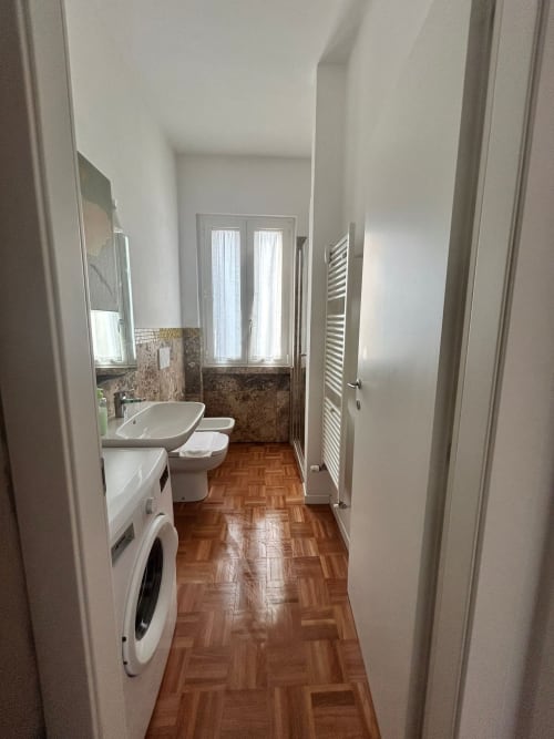 Modern bathroom at Villa Marisa in Pavia with sink, toilet, washing machine, herringbone flooring