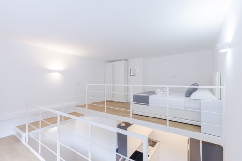 Camera da letto in loft moderno a Solumnia Milano con letto bianco, parete in vetro, pavimento in legno e vista sulla città