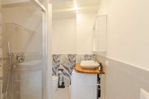 Bagno moderno a Vini Urban Loft Milano con doccia, lavabo con piano in legno e dettagli di piastrelle botaniche