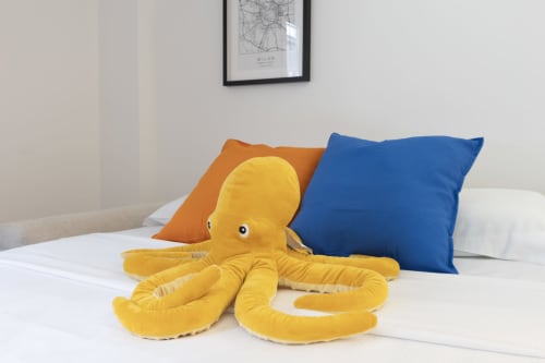Peluche polpo giallo sul letto con cuscini colorati nella camera da letto del loft urbano Solumnia Milano