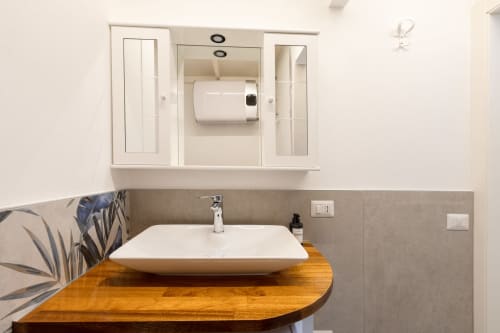 Lavabo moderno con bacile bianco in ceramica, piano di lavoro in legno e armadietto a specchio nel Vini Urban Loft di Solumnia
