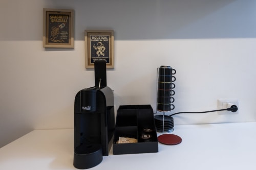 Macchina espresso nera con contenitore capsule e portavasi su superficie bianca in un loft urbano a Milano