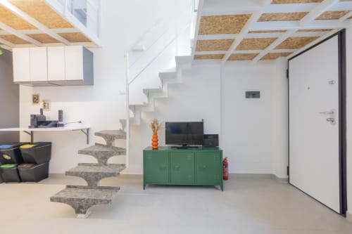 Interno loft moderno a Milano con scale sospese, mobile contenitore verde e angolo cottura attrezzato all'hotel Solumnia