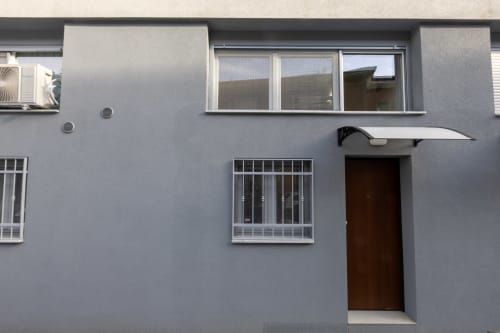Facciata moderna grigia del loft urbano Solumnia Milano con porta scura e finestre blindate