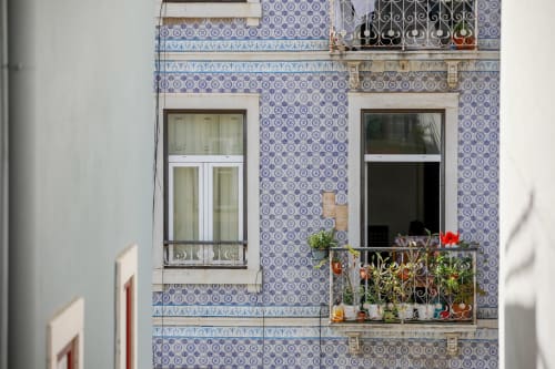 Portuguese tiled facade of Lisbon Poets Inn hostel with balcony featuring flowers and potted plants, city view apartment