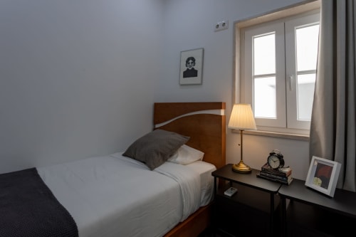Cozy bedroom at Lisbon Poets Inn hostel with single bed, desk lamp, nightstand, and window with natural light