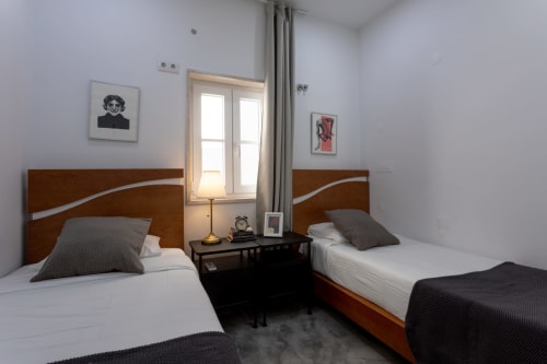Twin bedroom at Lisbon Poets Inn hostel with wooden beds, shared bathroom, air conditioning, and WiFi in Lisboa, Portugal