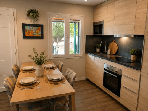 Cocina y comedor modernos en la cabaña La Casa del Lago con mesa de madera puesta para comer, gabinetes de madera clara y detalles en negro