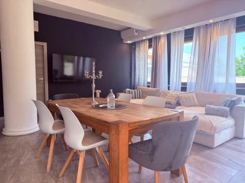 Modern apartment dining area with wooden table, white chairs, dark accent wall, and living room at STAYIN VERONA hotel