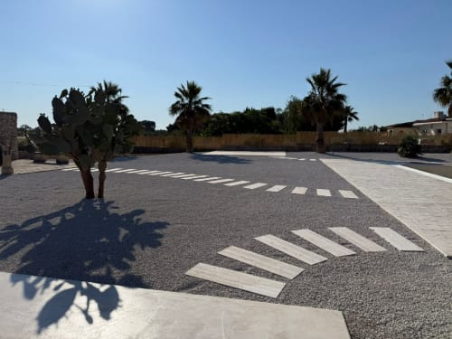 Parking du B&B Hélios à Nardò avec passage clouté, palmiers et ciel bleu dégagé
