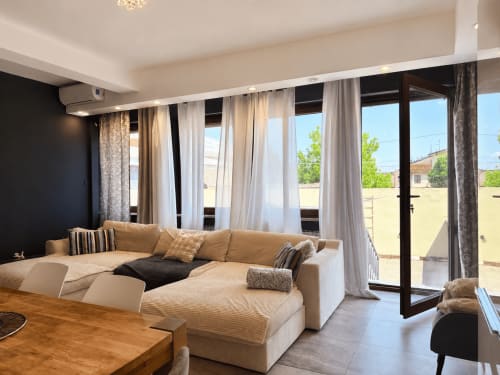 Soggiorno moderno a Verona con divano componibile beige, ampie finestre e accesso alla terrazza