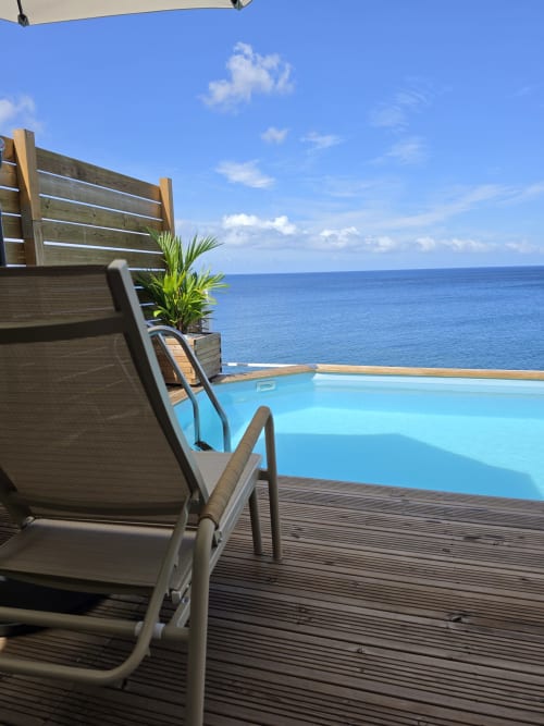 Chaise longue sur terrasse en bois surplombant une piscine à débordement et la mer des Caraïbes turquoise à Clémara Evasion, Martinique