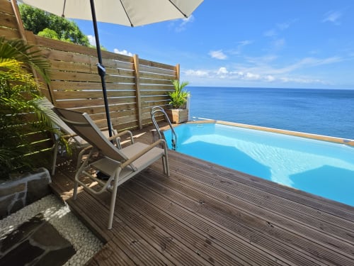 Terrasse vue mer à Clémara Evasion avec piscine à débordement, transat, parasol et mer Caraïbe turquoise à la Martinique