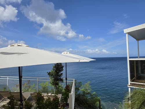 Terrasse face à l'océan de Clémara Evasion avec parasols blancs, vue sur la mer et mobilier côtier moderne à la Martinique