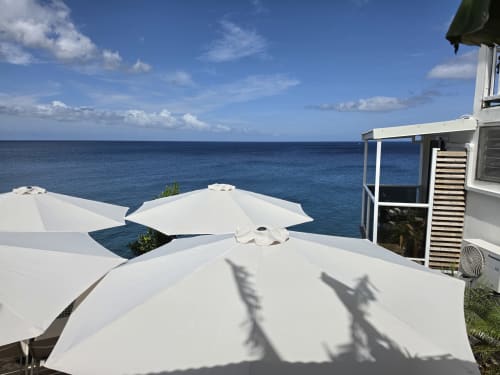 Terrasse de Clémara Evasion avec parasols blancs vue sur la mer des Caraïbes à Schœlcher, Martinique