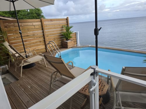 Terrasse face à l'océan avec piscine privée, chaises longues, écran en bois et vue sur mer à Clémara Evasion