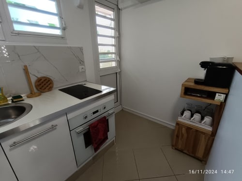 Cuisine moderne du gîte Clémara Evasion en Martinique, avec électroménagers blancs, cuisinière électrique, rangements en bois et vue océan