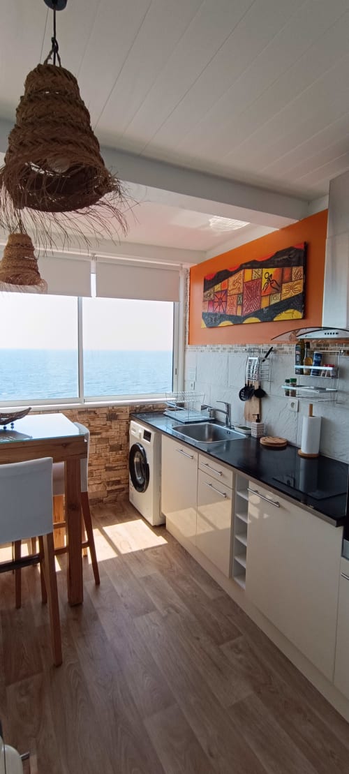 Cuisine moderne avec vue mer au gîte Clémara Evasion en Martinique, armoires blanches et océan visible par les grandes fenêtres