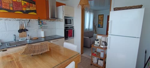 Cuisine ouverte sur le séjour de l'appartement Oasis à Clémara Evasion à Schœlcher avec table à manger en bois, style moderne