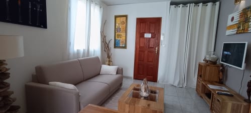 Salon moderne de l'appartement Oasis à Clémara Evasion, Schœlcher avec canapé gris, table en bois, TV et porte rouge