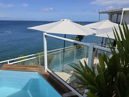 Terrasse de l'appartement Clémara Evasion Horizon avec piscine à débordement, parasols blancs et vue océan en Martinique