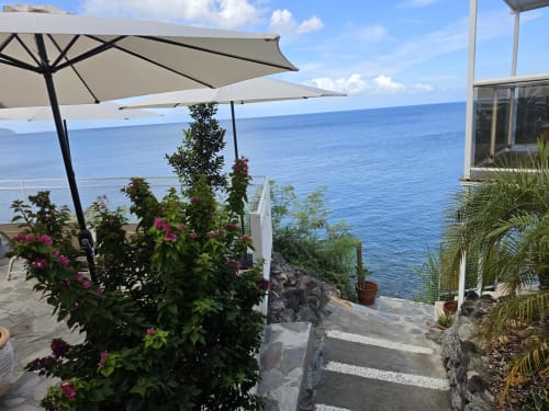 Terrasse de Clémara Evasion surplombant la mer des Caraïbes avec parasols, fleurs tropicales et vue océan en Martinique