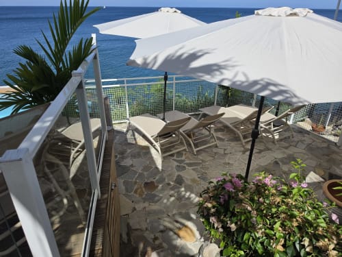 Terrasse face à l'océan à Clémara Evasion en Martinique avec parasols blancs, transats et vue sur mer