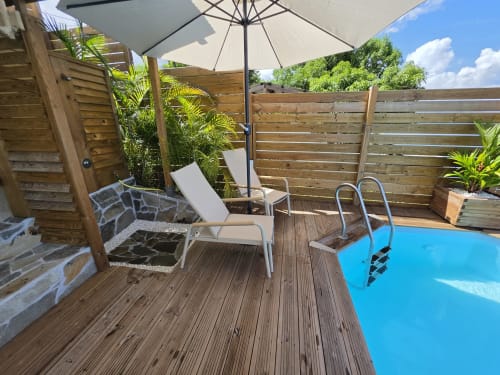 Terrasse avec piscine privée à Clémara Evasion : transats, parasol, terrasse en bois et plantes tropicales à la Martinique