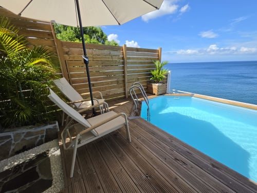 Terrasse avec vue océan à Clémara Evasion : piscine à débordement, transat, parasol et mer turquoise en Martinique