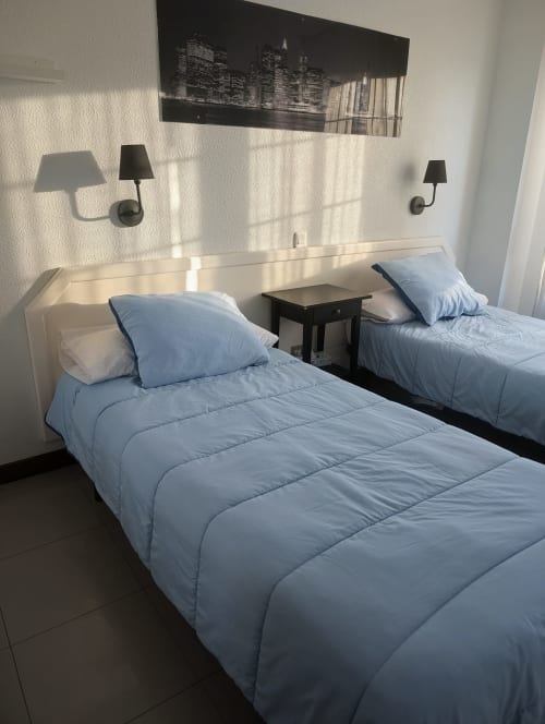 Habitación doble con ropa de cama azul claro y cabecero blanco en La Ballena B&B, Santoña, España