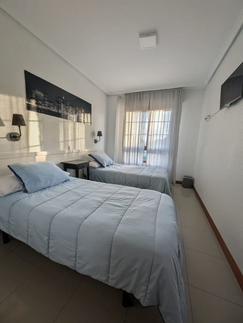 Habitación doble en La Ballena B&B en Santoña con vistas a la ciudad, ropa de cama blanca y comodidades modernas