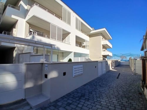 Modern white apartment building at Pescara INN with balconies, parking area, and clear blue sky, sea view accommodation in