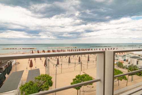 Pescara beach with sea view from Pescara INN balcony, rows of beach umbrellas and volleyball nets on sand