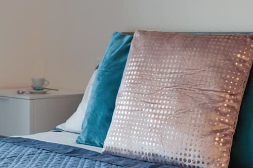 Cozy bedroom at Pescara INN with decorative pillows on bed and side table with cup