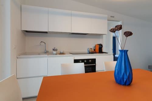 Modern kitchen with white cabinets, orange dining table, and blue vase at Pescara INN apartment