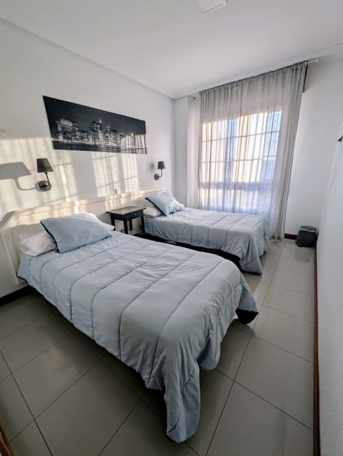 Twin bedroom with light blue bedding and modern amenities at La Ballena B&B in Santoña, Spain