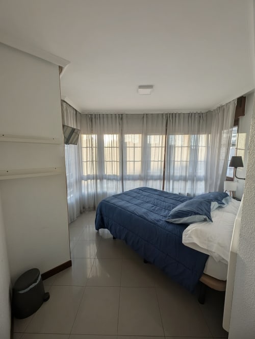 Habitación luminosa con cama doble, balcón con vistas a la ciudad y cortinas translúcidas en La Ballena B&B en Santoña