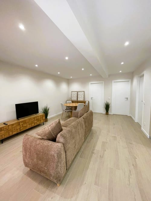 Sala de estar moderna na Villa Sotto Mayor com sofá bege, móveis de madeira e iluminação embutida