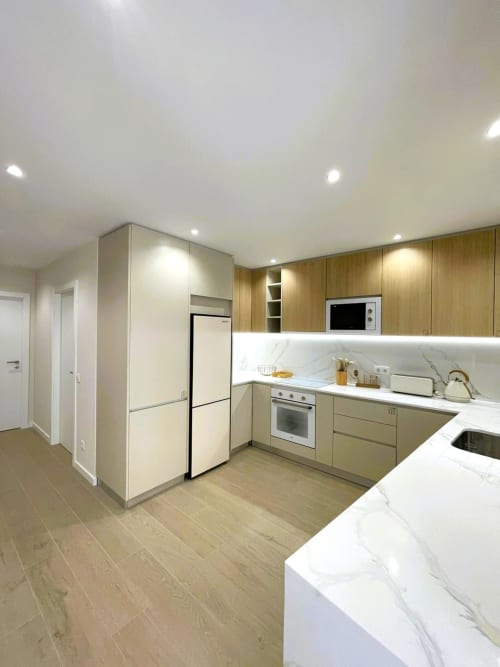 Cozinha moderna no apartamento Villa Sotto Mayor em Figueira da Foz com móveis em madeira, bancadas em mármore e acesso à vista do mar