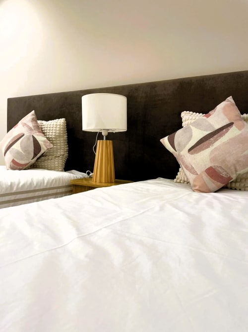 Quarto aconchegante na Villa Sotto Mayor com cabeceira escura, almofadas estampadas, luminária de madeira e roupa de cama branca em Figueira da Foz