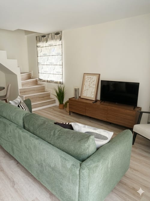 Sala de estar moderna com sofá verde, móvel de madeira para TV e escadas na Villa Sotto Mayor, Figueira da Foz